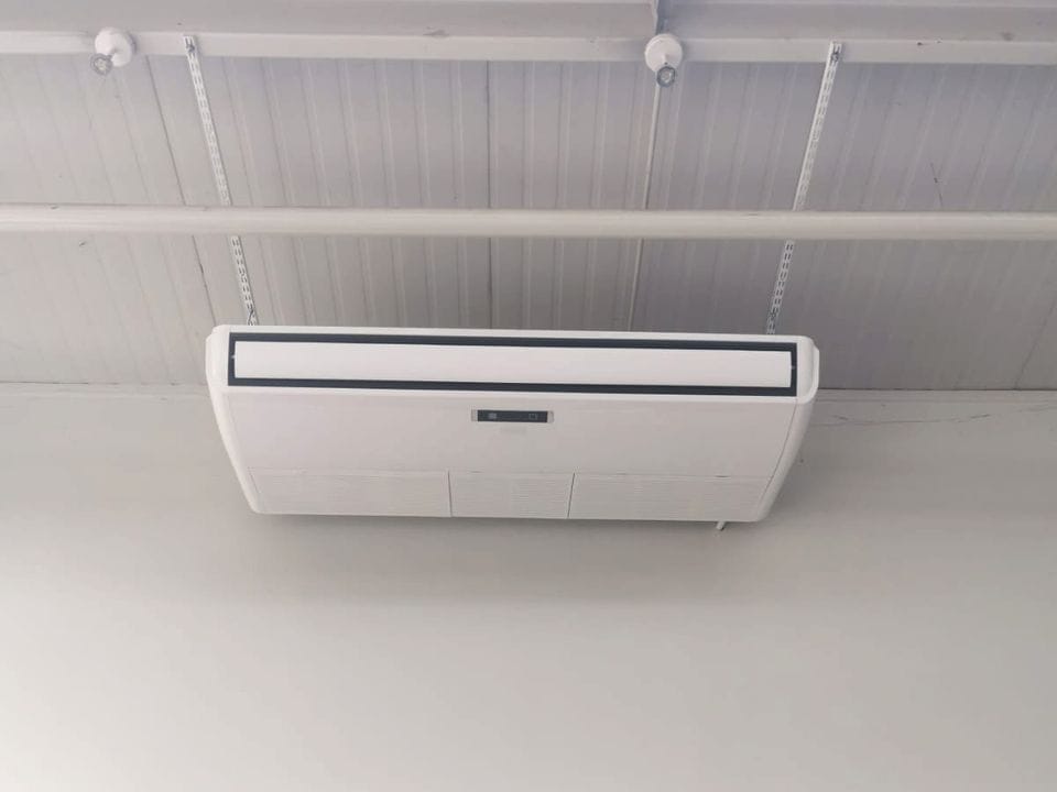 White indoor unit hung from the roof beams of a high room